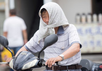 FILE PHOTO: A man is seen with a towel tied around his head to escape hot weather as a heat wave hits Hangzhou