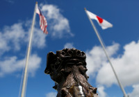 The U.S. and Japanese national flags are hoisted next to a traditional Okinawan Shisa statue at the U.S. Marine's Camp Foster in Ginowan